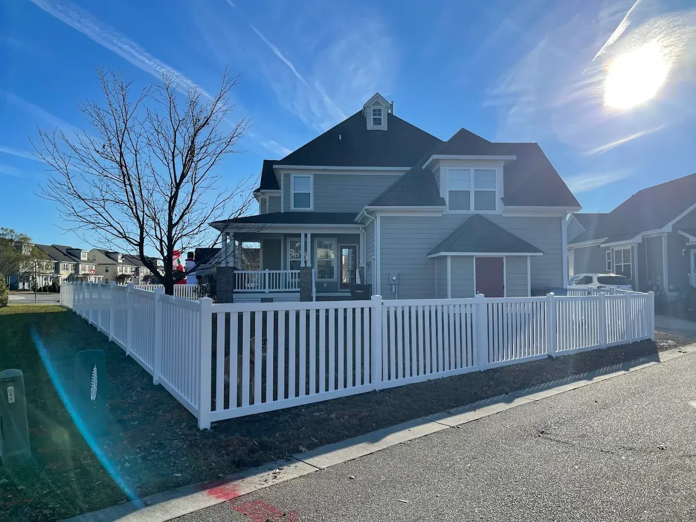 Two-story house with white picket fence on a sunny day.