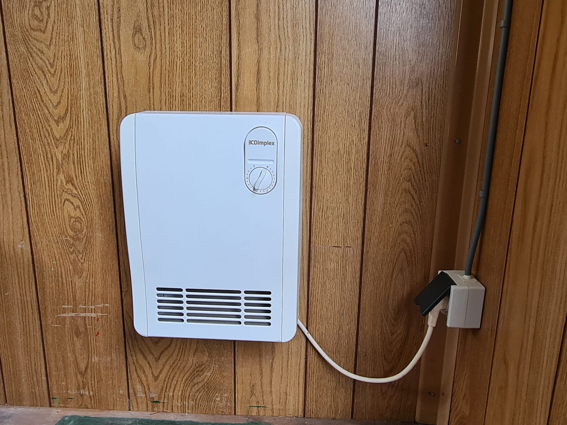 Een witte kachel is op een houten muur aangesloten.