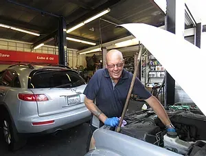 Mechanic Smiling While Servicing Engine Bay | Woodland Hills Auto Service
