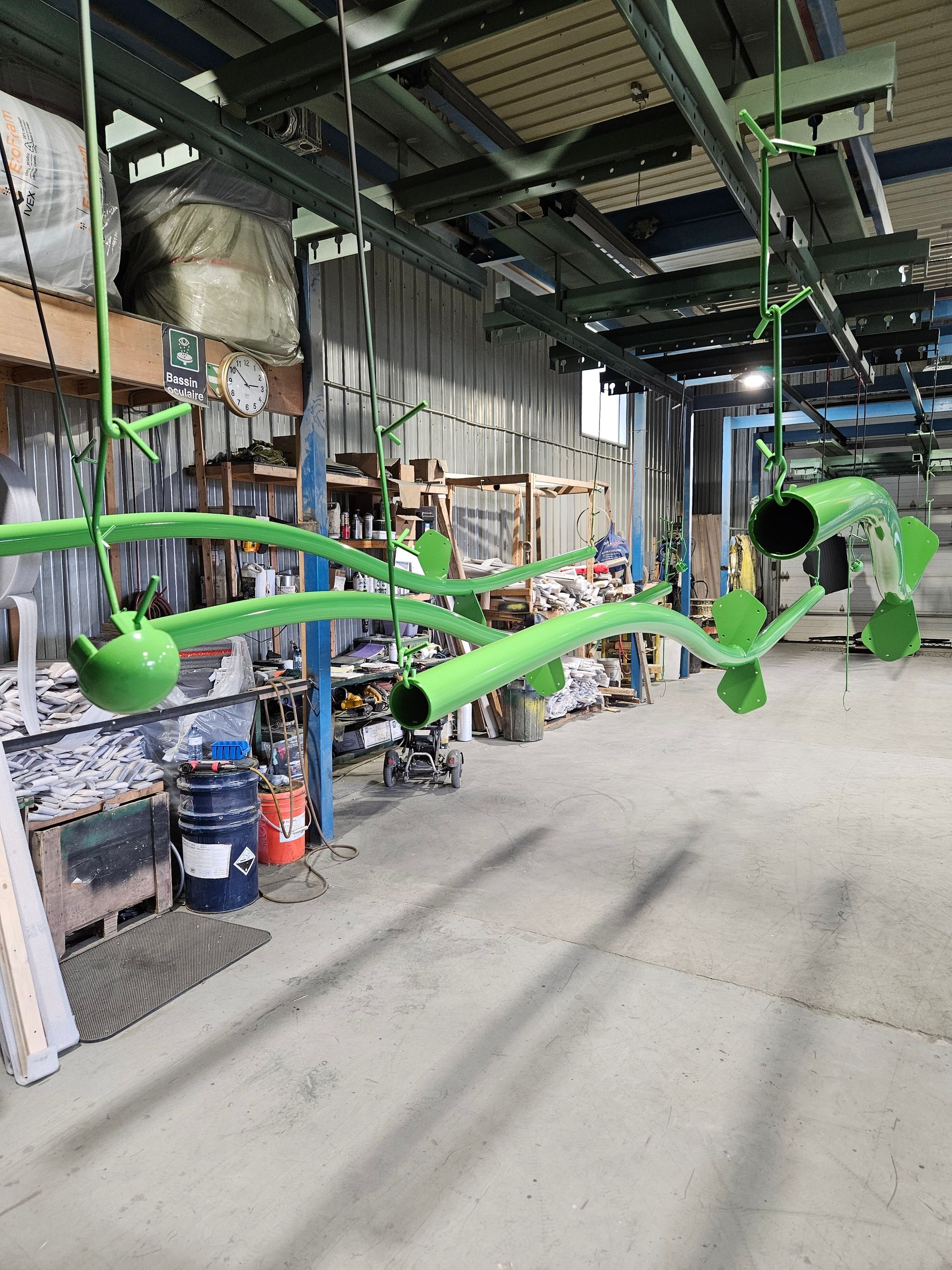 Un entrepôt avec des tuyaux verts suspendus au plafond.