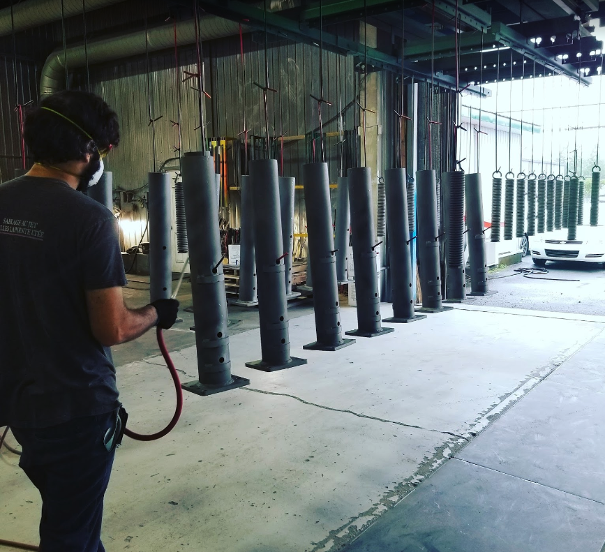 Un homme portant un masque se tient devant une rangée de poteaux métalliques