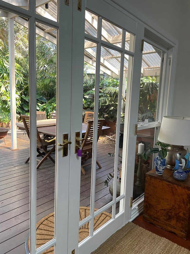 A Room with French Doors Leading to A Deck and A Table and Chairs — Tradewind Building Maintenance in Wollongong,NSW