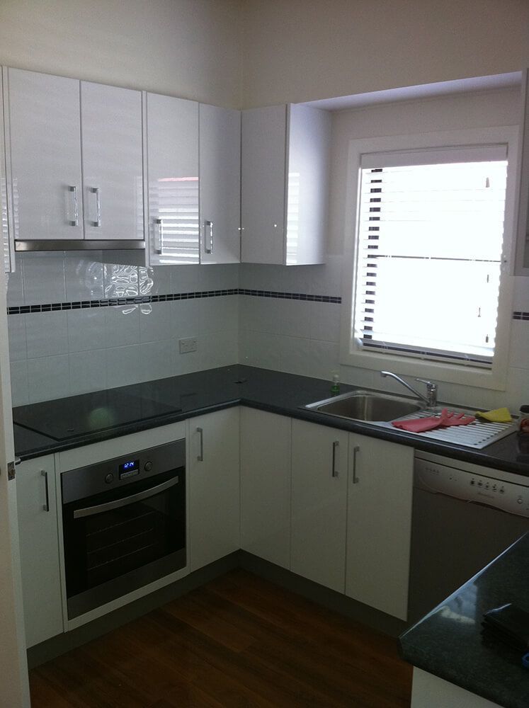 A Kitchen with White Cabinets and Black Counter Tops — Tradewind Building Maintenance in Balgownie,NSW