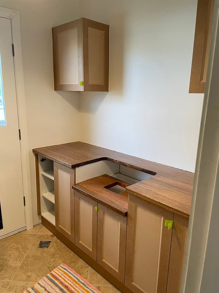 A Kitchen with Wooden Cabinets and A Striped Rug on The Floor — Tradewind Building Maintenance in Balgownie,NSW