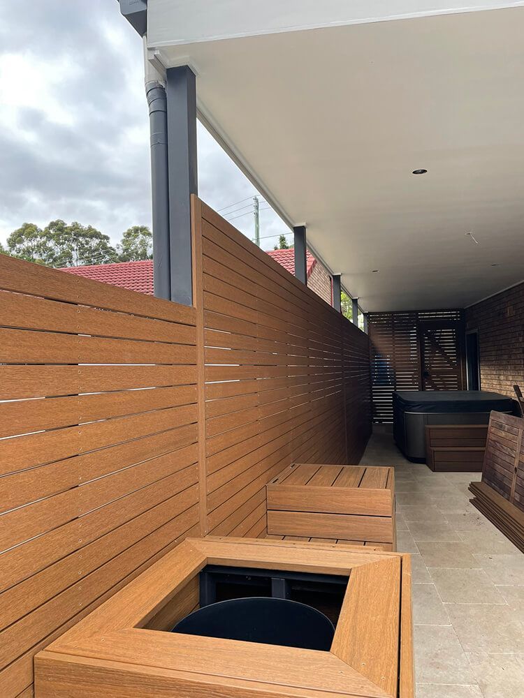 A Wooden Fence Surrounds a Patio with A Hot Tub in The Background — Tradewind Building Maintenance in Woonona,NSW