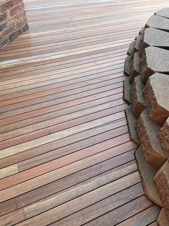 A Wooden Deck with A Brick Wall in The Background — Tradewind Building Maintenance in Bulli,NSW