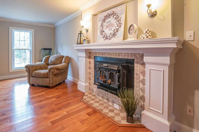 A living room with hardwood floors and a custom fireplace. An armchair sits in the far corner.