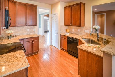 A kitchen with hardwood floors , granite counter tops , and wooden cabinets.