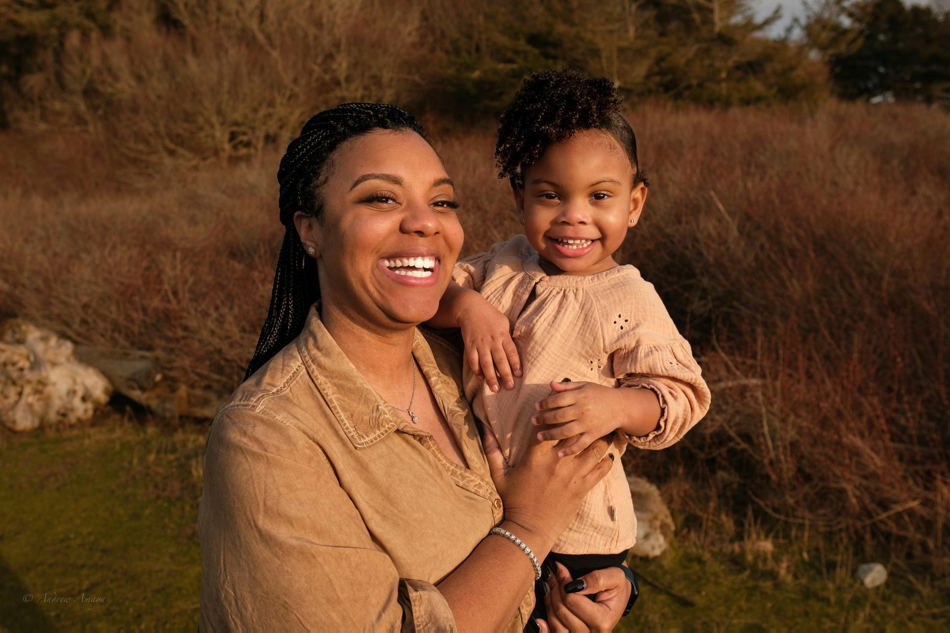 A woman is holding a little girl in her arms and smiling.