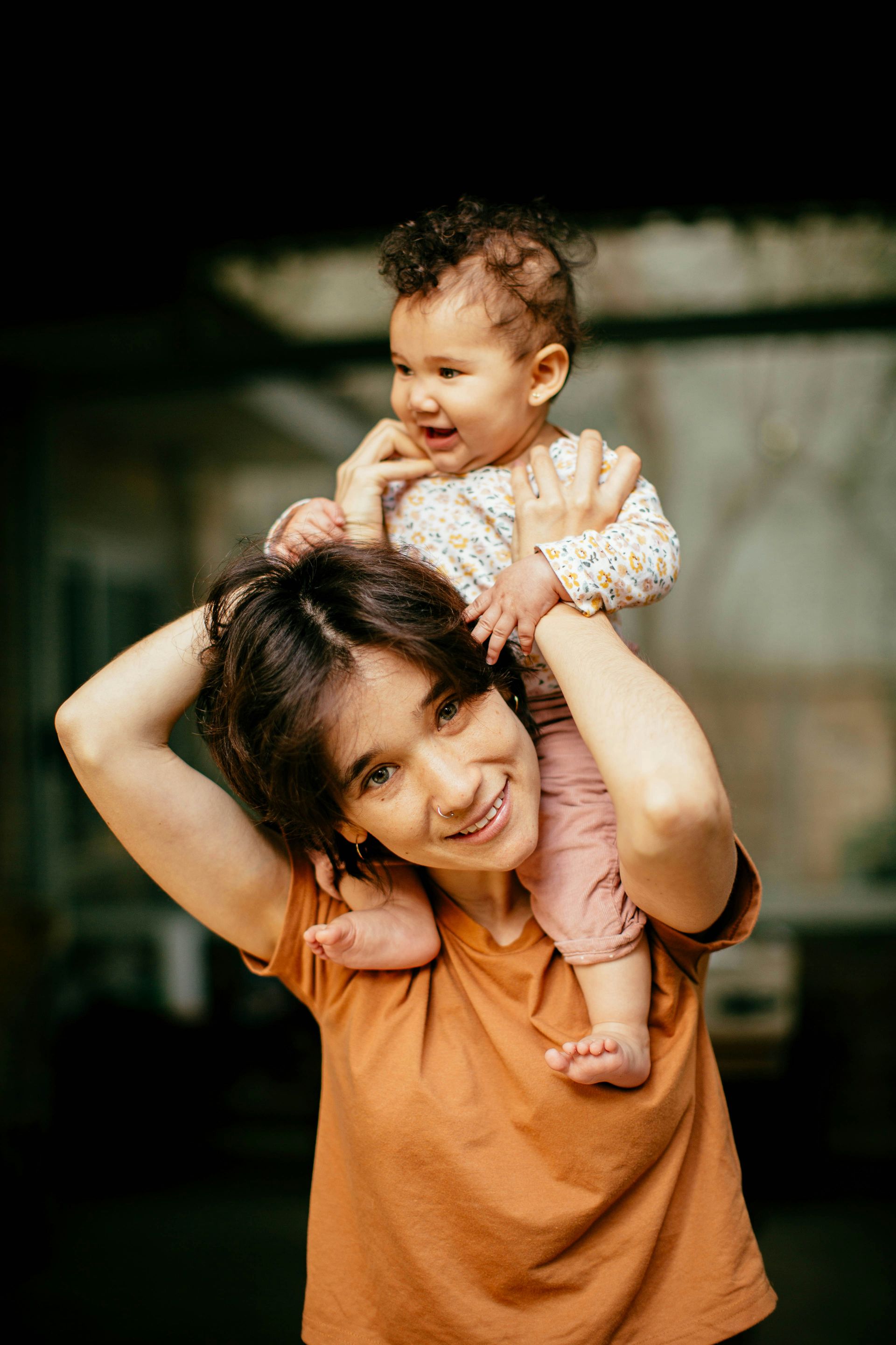 A woman is carrying a baby on her shoulders.