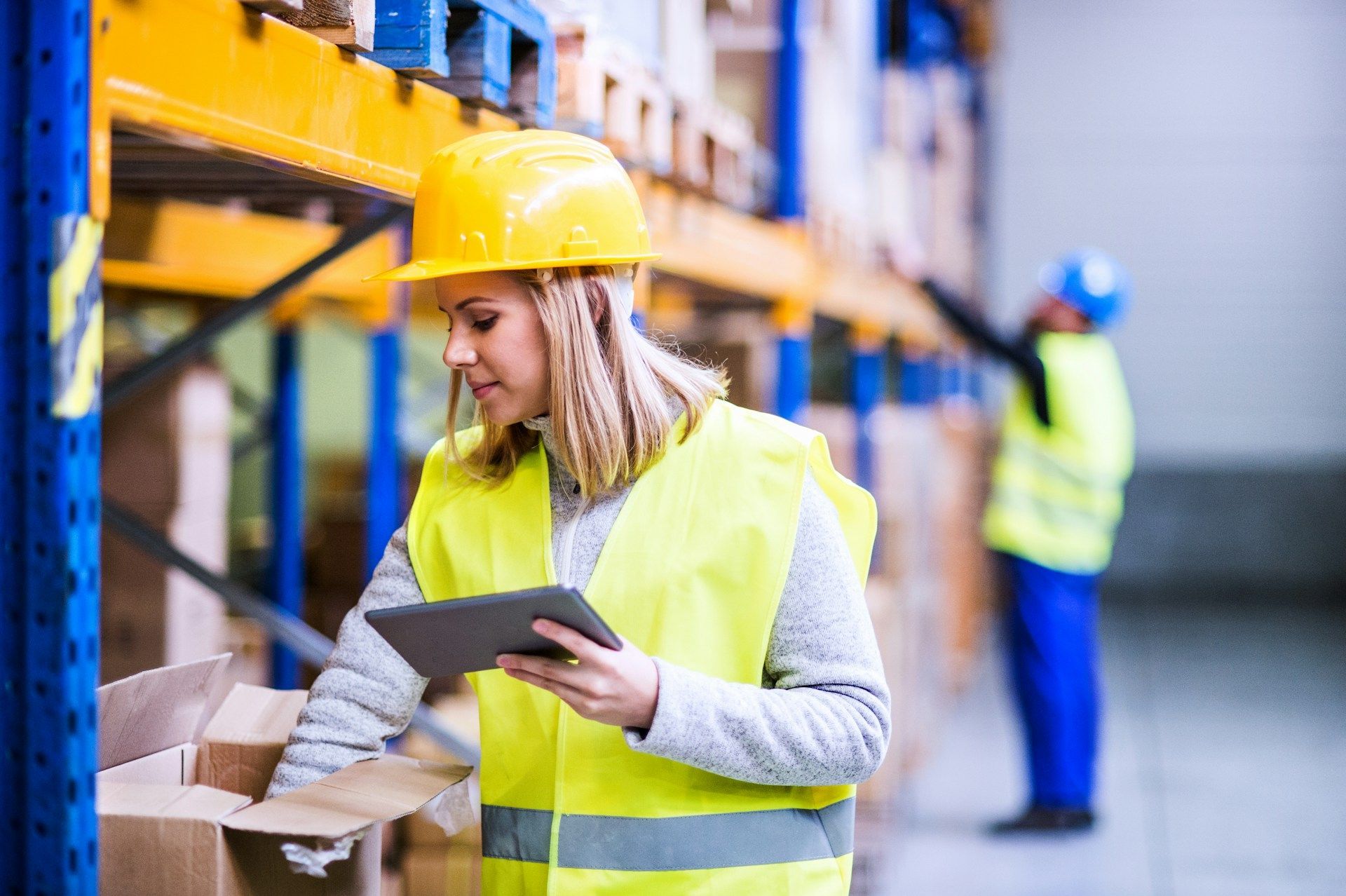A woman is using a tablet in a warehouse.