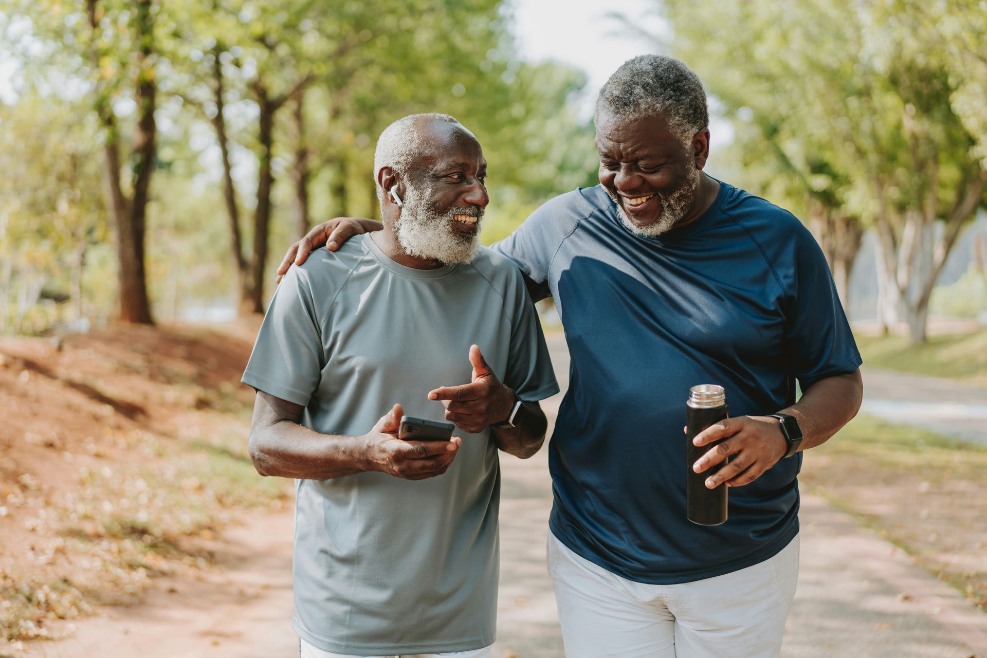 Two older men are walking down a path and talking to each other.