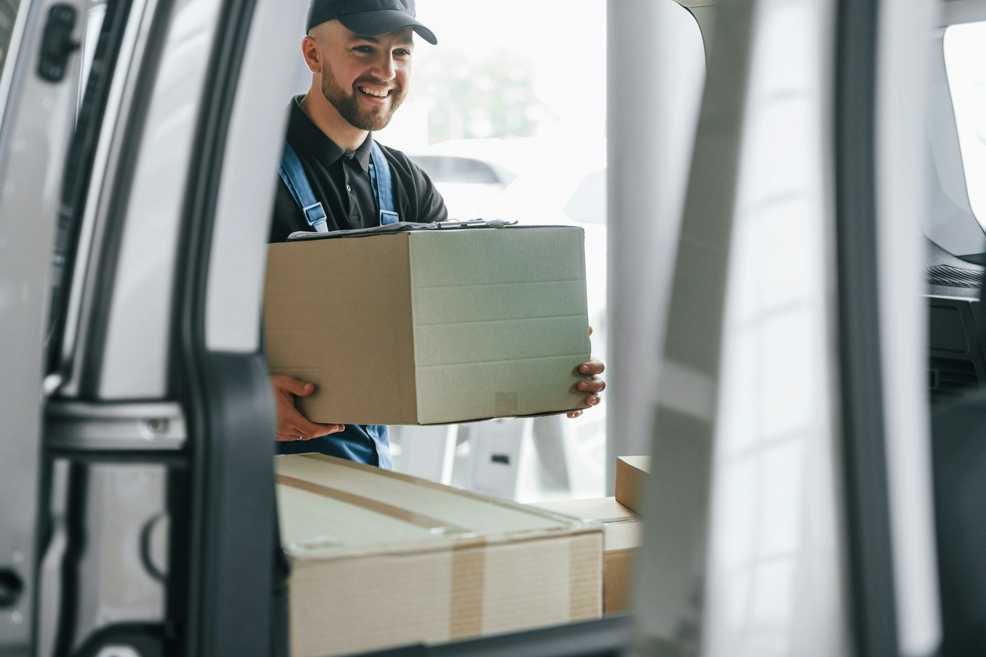 A delivery man is carrying a cardboard box out of a van.