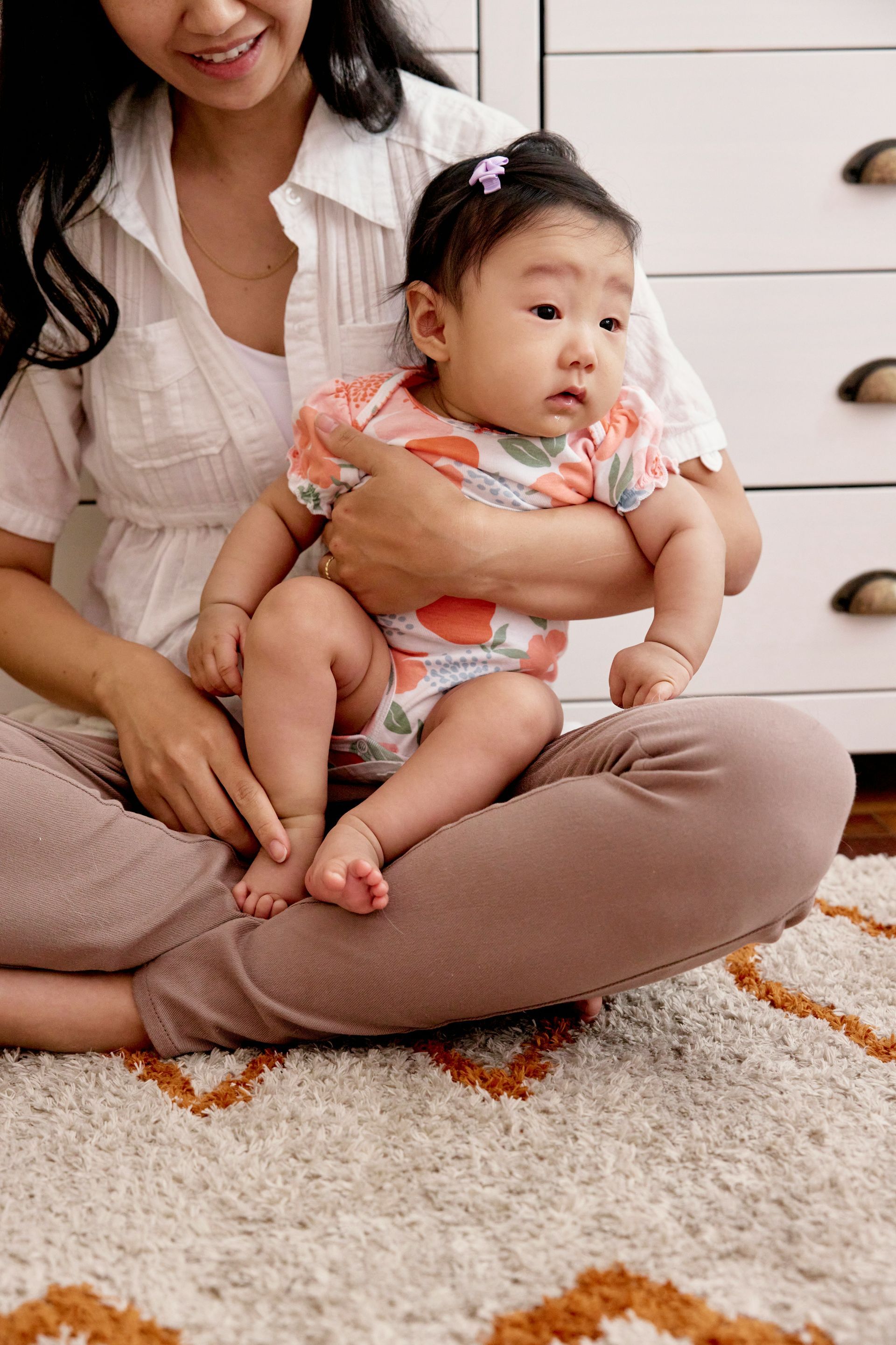 A woman is sitting on the floor holding a baby.