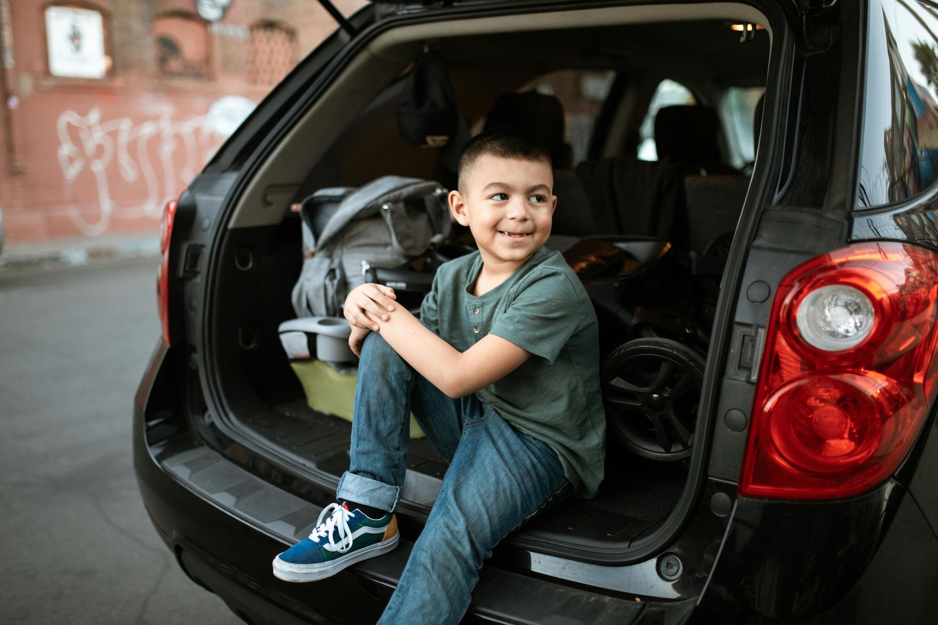 A young boy is sitting in the back of a car.