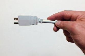 A person is holding a white plug in their hand