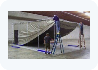 A group of people are working on a tent in a warehouse.