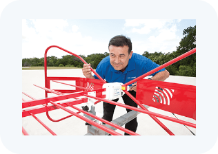 A man in a blue shirt is working on a red and white object.