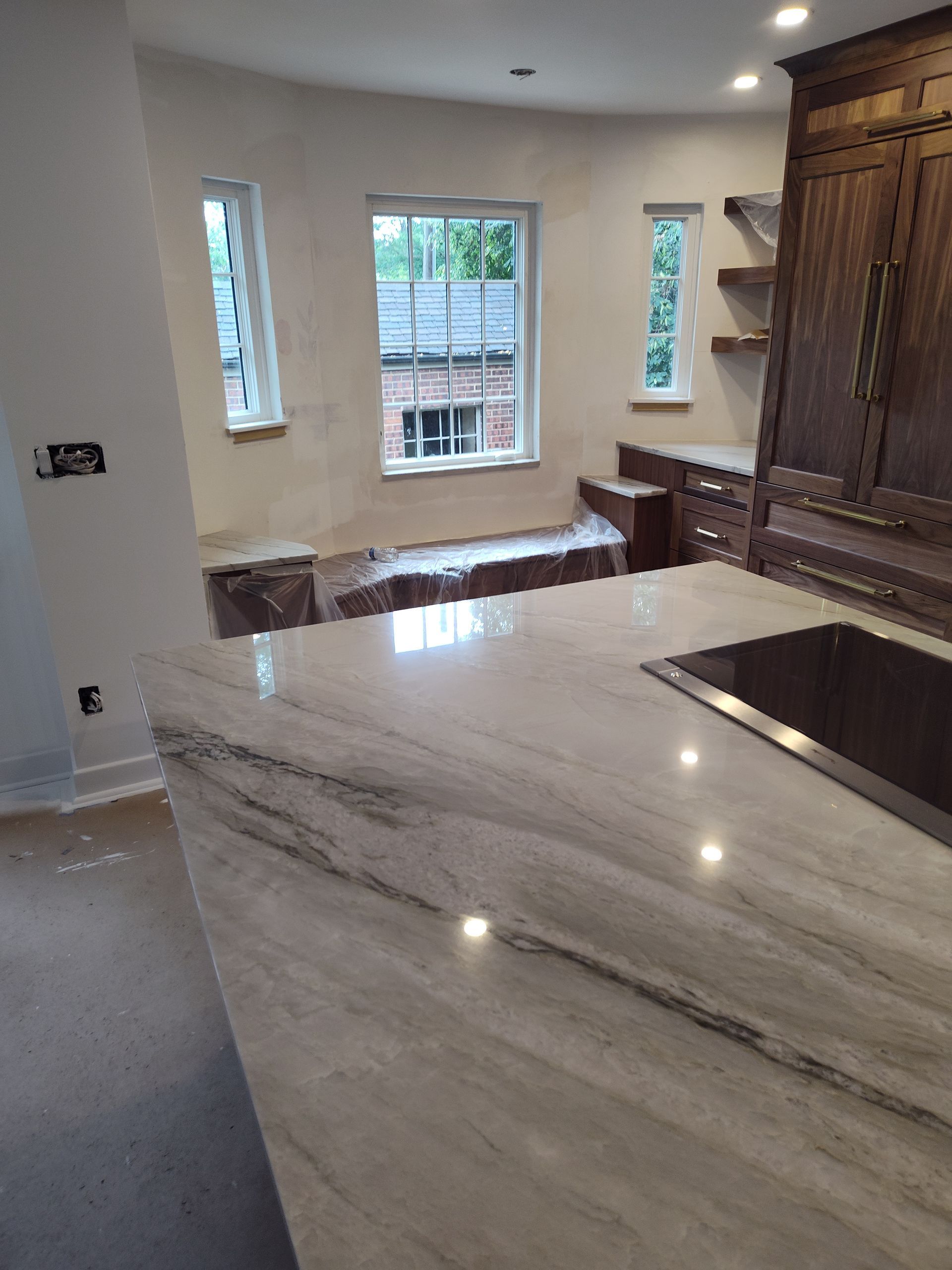 Kitchen with marble countertop, dark cabinetry, and windows overlooking brick building.