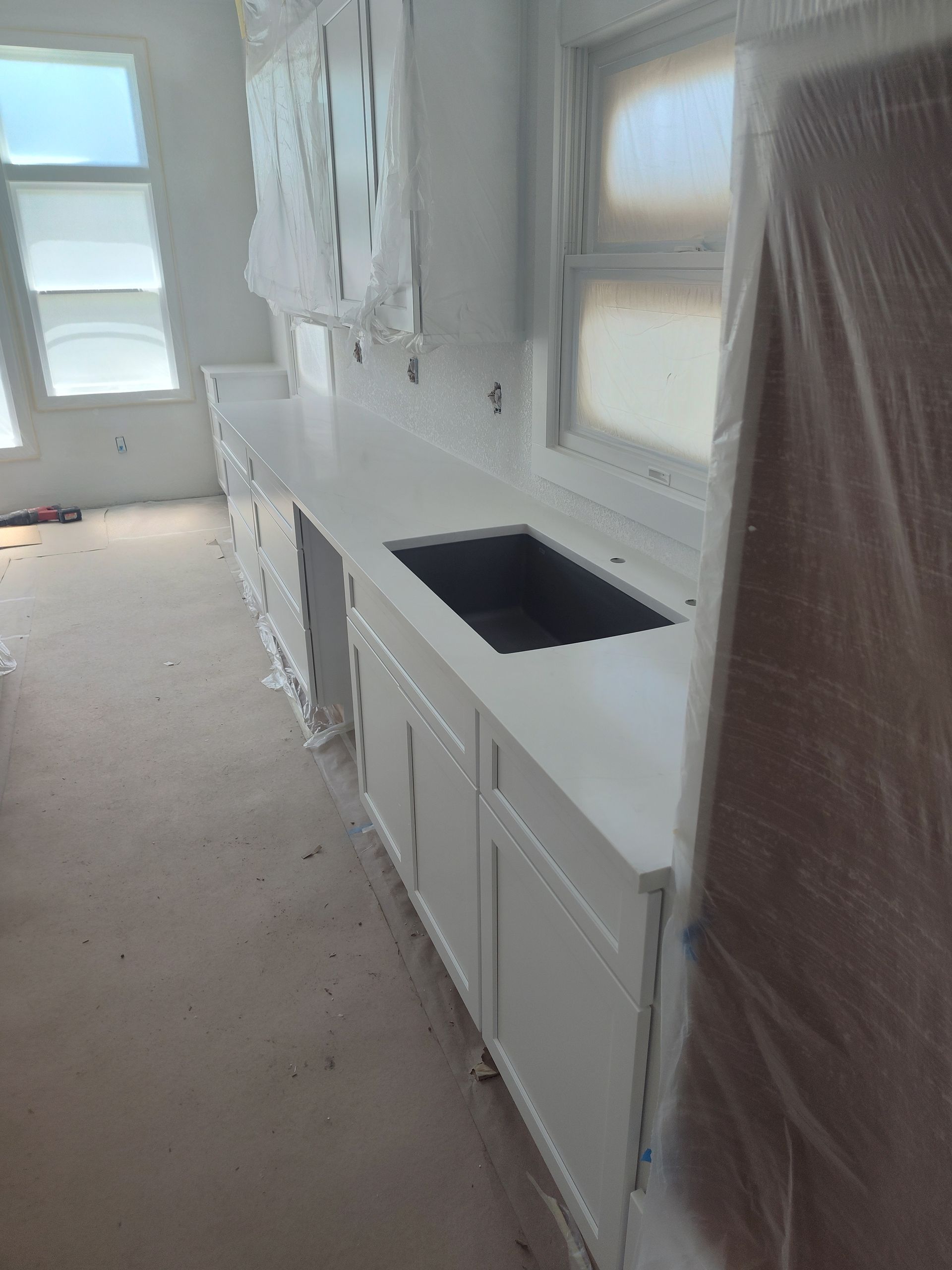 White kitchen cabinets with a sink, under construction.