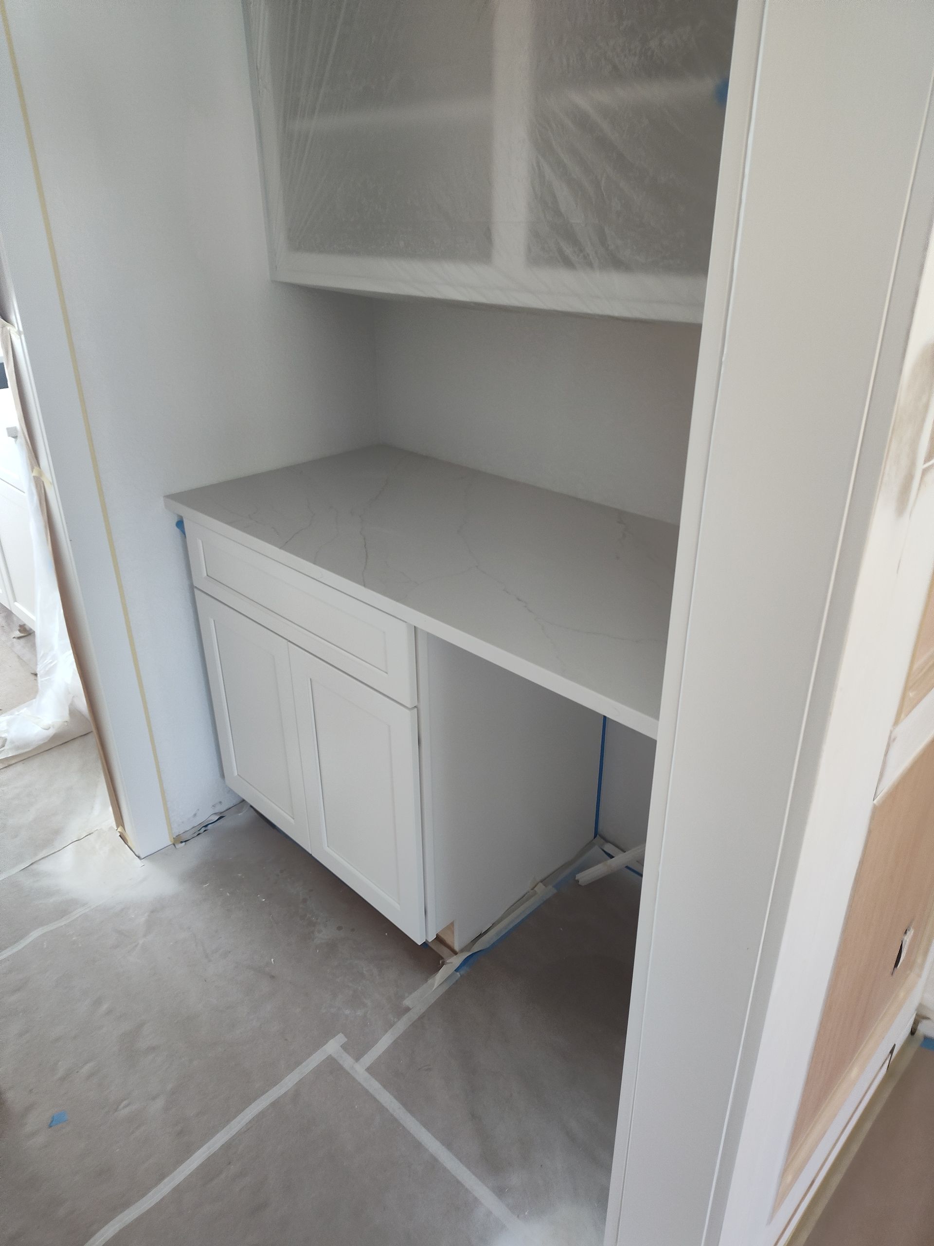 White built-in desk in a room, with overhead cabinets.