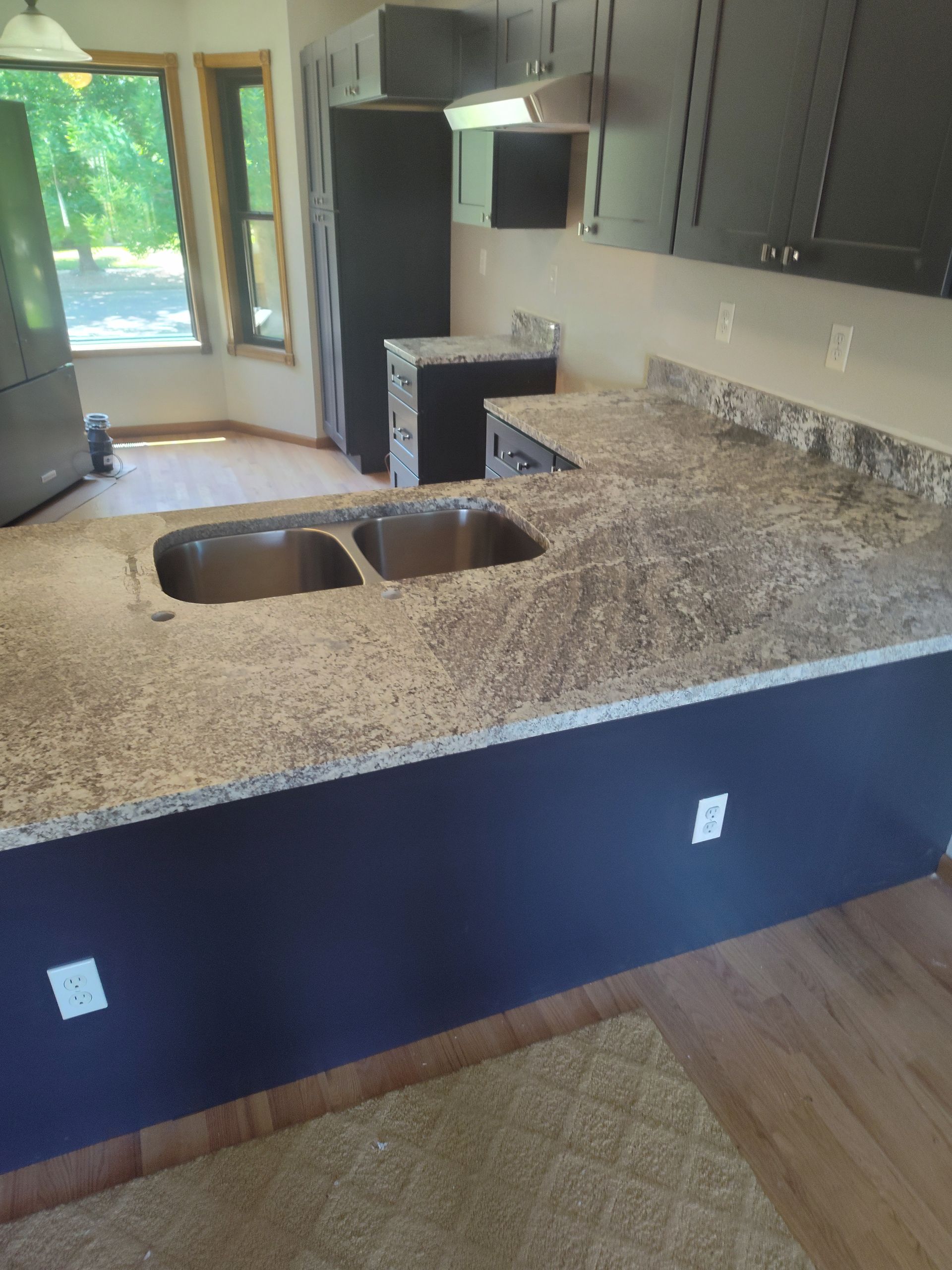 Kitchen with dark cabinets, granite countertops, and a double sink.