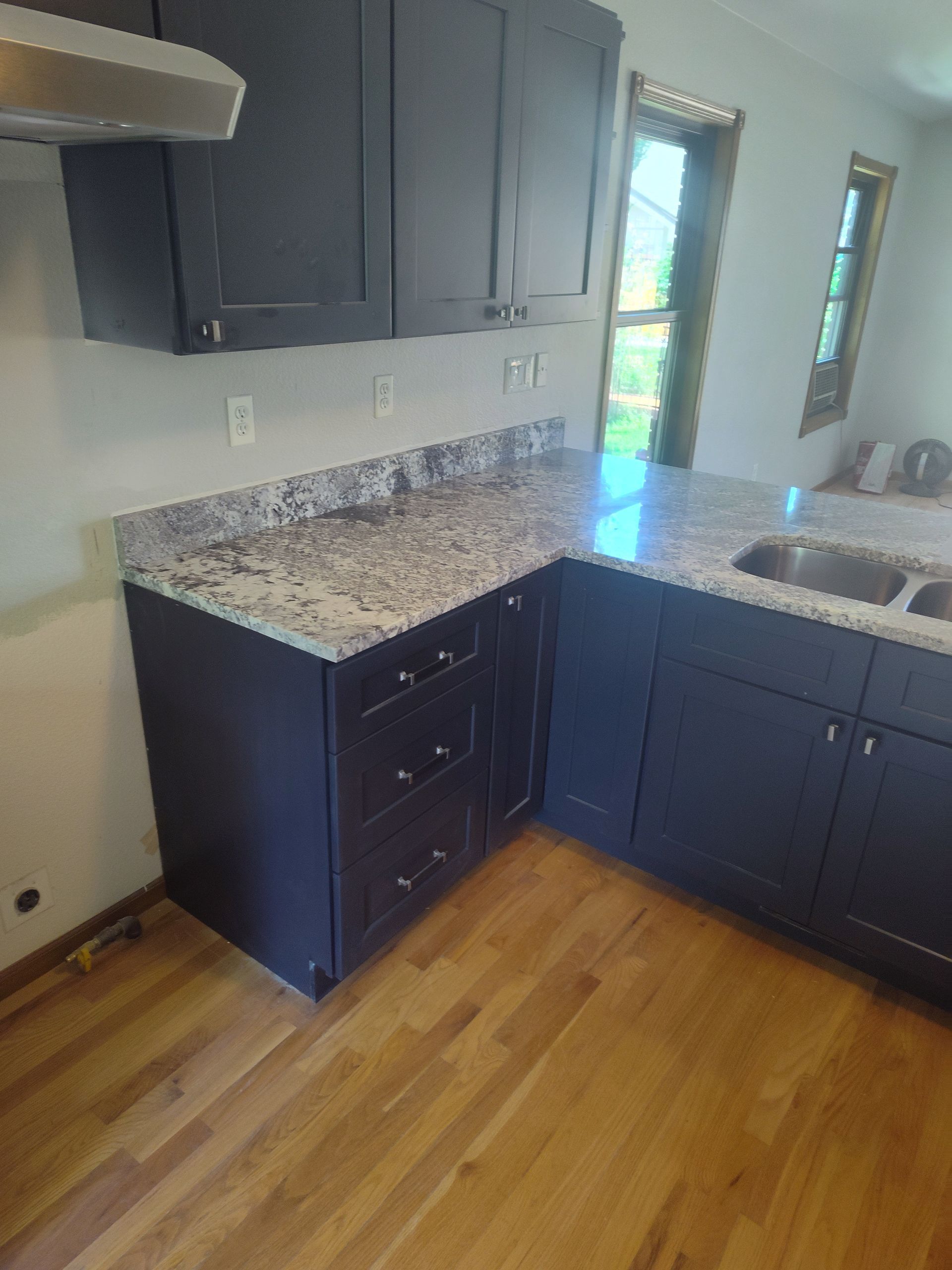Dark kitchen cabinets with granite countertops, hardwood floors.