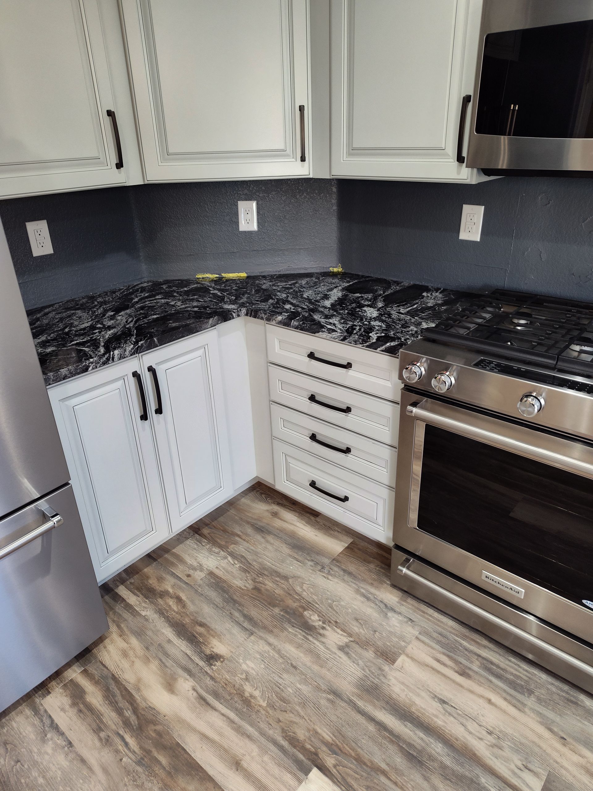 Kitchen with white cabinets, black countertops, and stainless steel appliances.