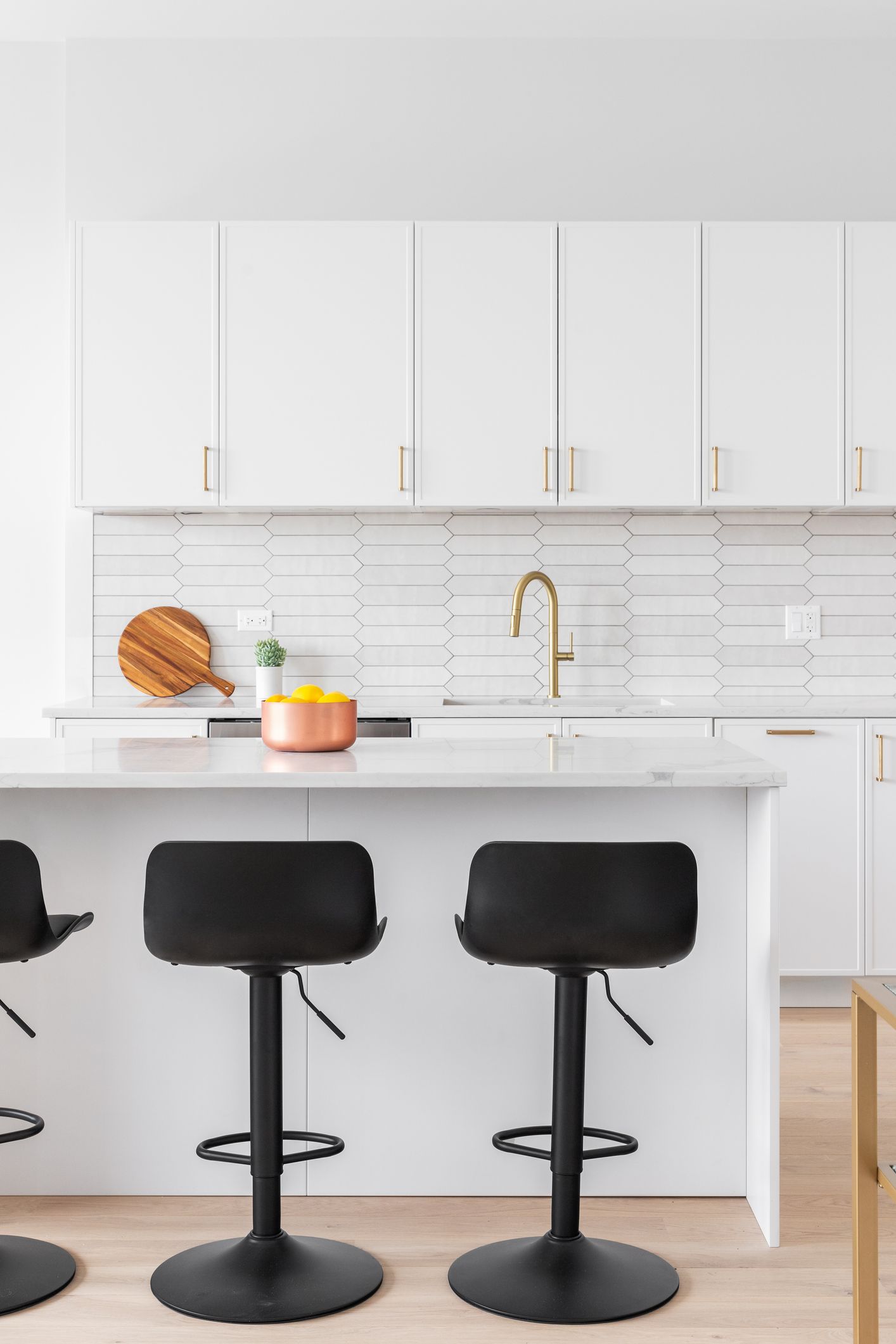 Modern white kitchen with black bar stools.