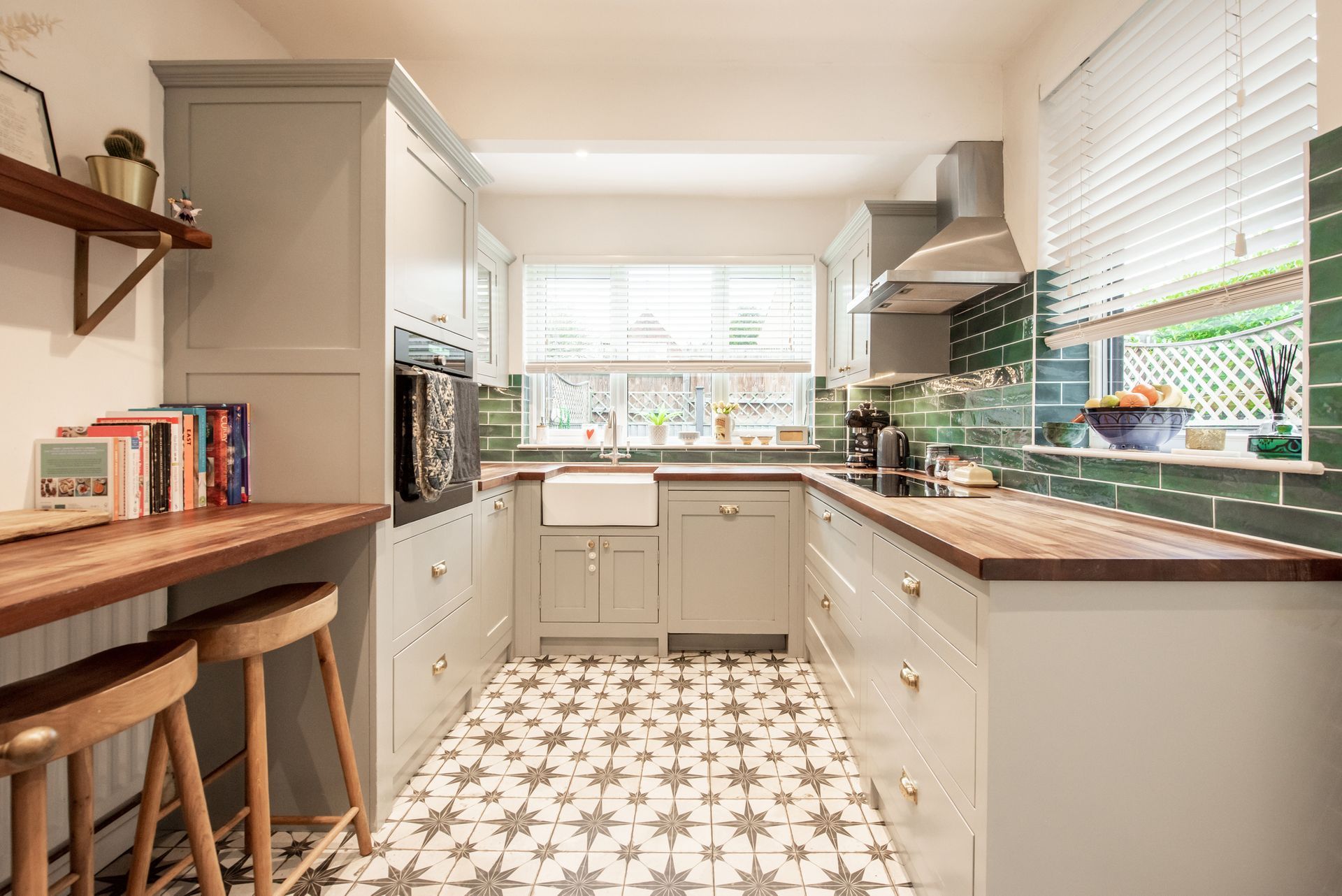 U-shaped kitchen with gray cabinets, wood countertops, patterned floor, and green tiled backsplash.