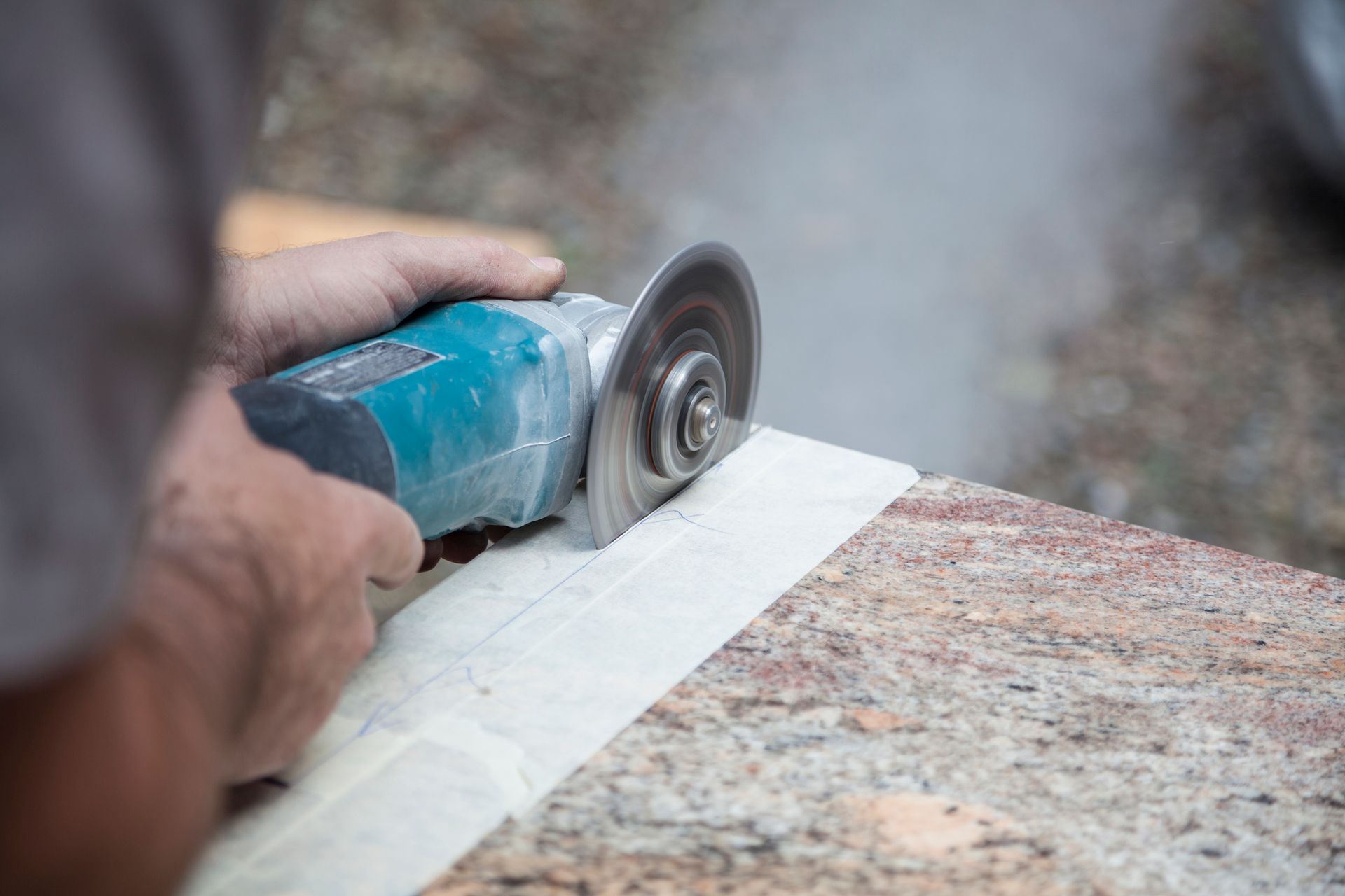 Person using a power grinder to cut a piece of stone. Smoke is visible.