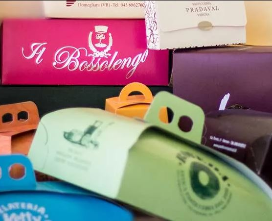 Una collezione di scatole regalo e contenitori per alimenti colorati e di marca, impilati uno sull'altro.