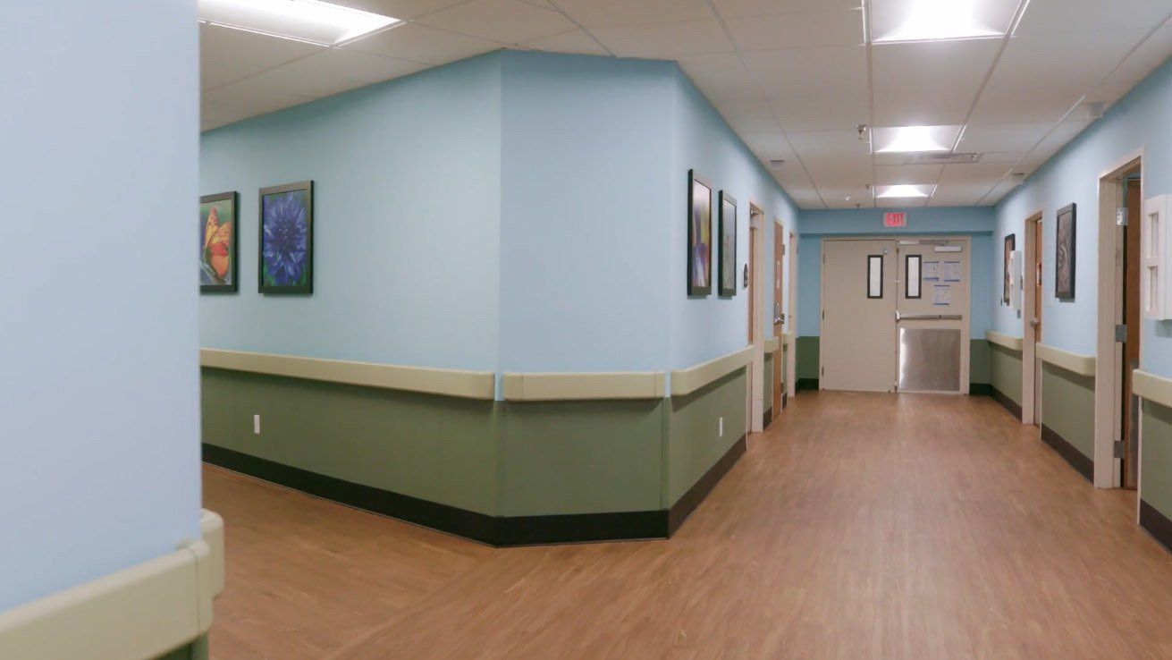 A hospital hallway with blue walls and green trim