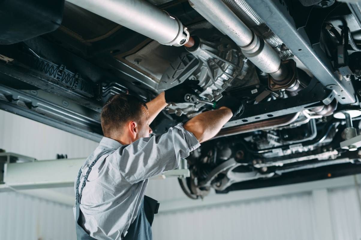 Mechanic working on a lifted car in a transmission mechanic shop near Cincinnati, OH