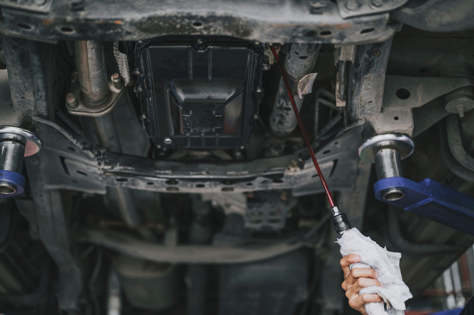 Mechanic performing a transmission flush underneath a vehicle.