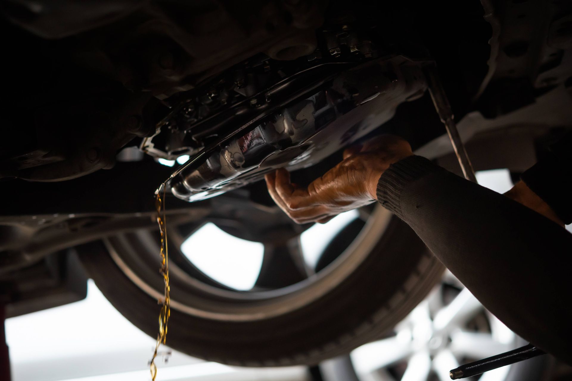 Car mechanic draining transmission fluid in a body shop near Sharonville, OH