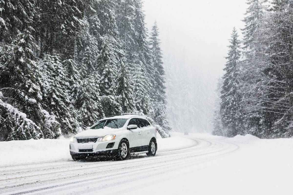 Modern white car driving on a snowy road at Mr. Transmission near Sharonville, OH