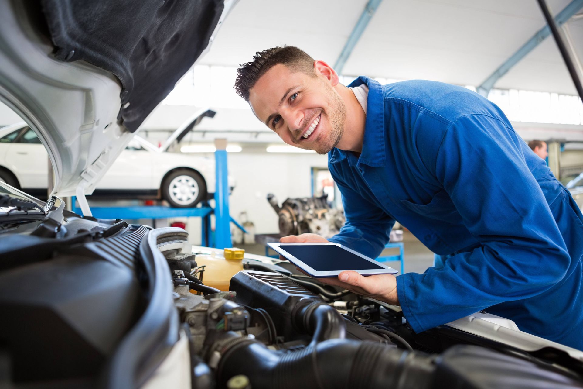 Car mechanic working on the transmission of a vehicle while holding a tablet at Mr. Transmission nea