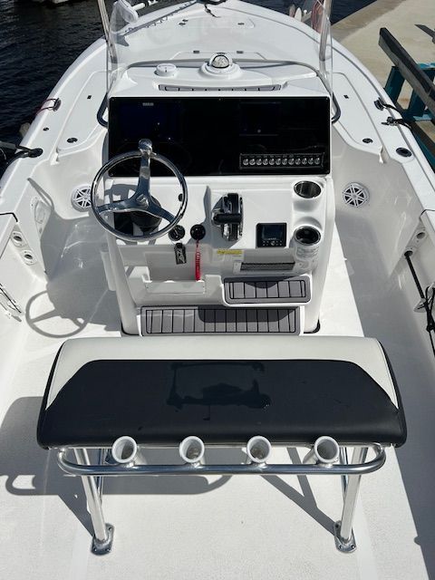 White boat console with steering wheel, gauges, and bench seat with rod holders.