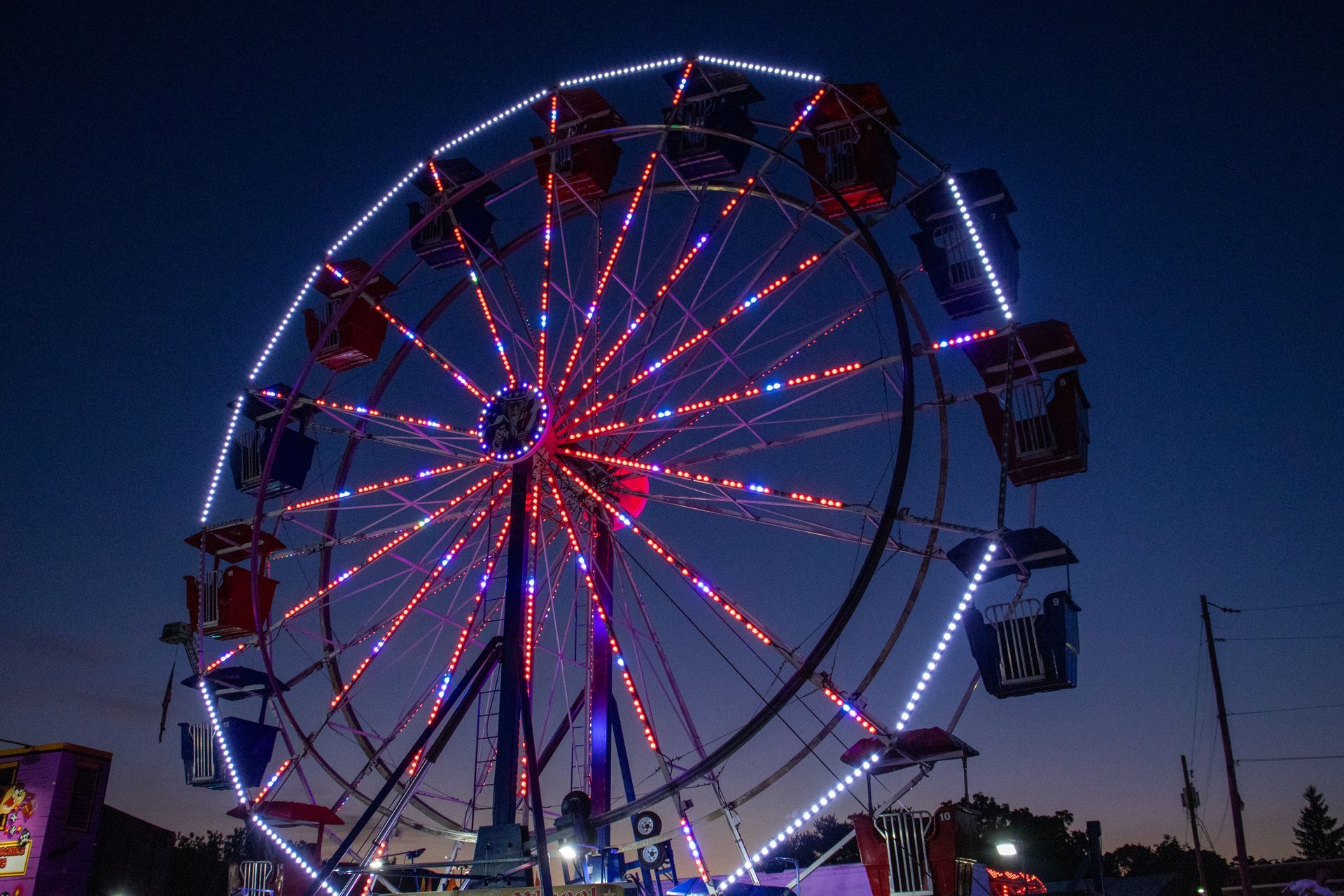 A ferris wheel is lit up at night at a carnival.