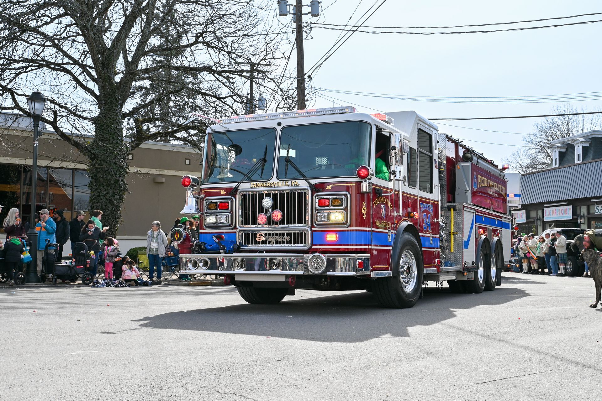 A fire truck is driving in a parade.