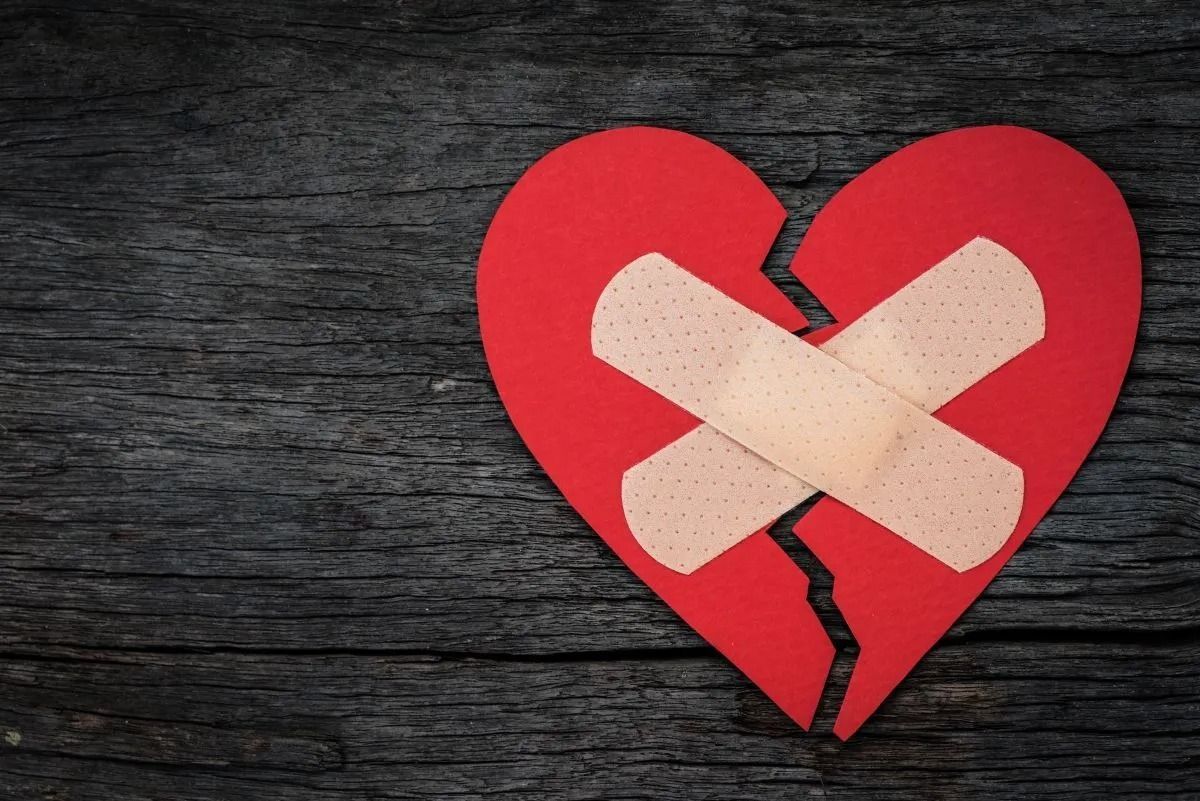 graphic of a broken heart held together with bandages on wood background