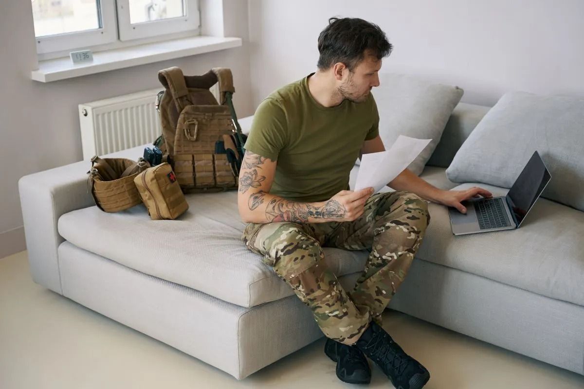 Soldier Sitting on Couch Planning with Paper and Laptop