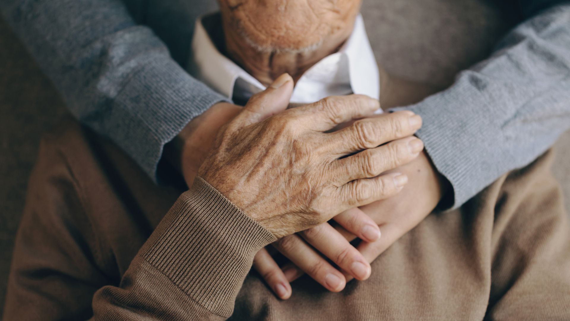 elderly person's hands being held
