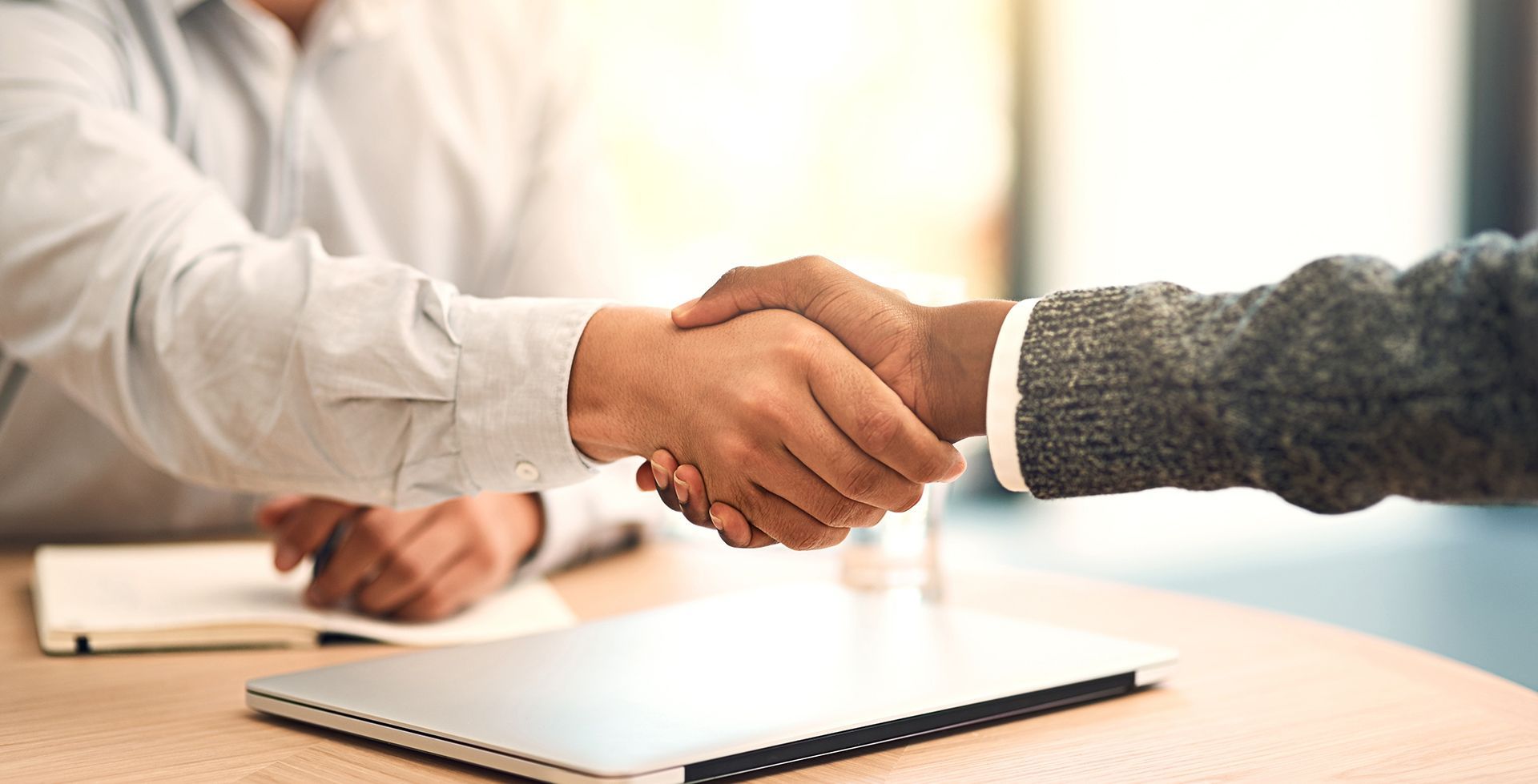 two people shaking hands across a desk