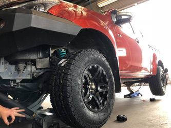 A Person Is Working On A Red Truck In A Garage — Torque Tyres & Trailer Spares Mackay in Mackay, QLD