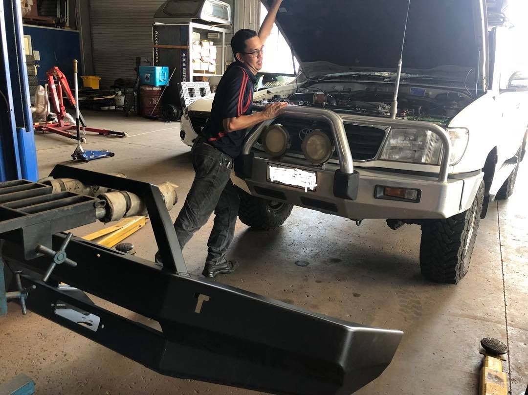 A Man Is Working On A Car In A Garage — Torque Tyres & Trailer Spares Mackay in Mackay, QLD
