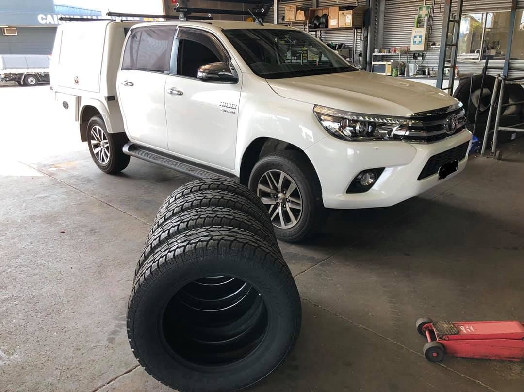 A White Truck Is Parked Next To A Pile Of Tires In A Garage — Torque Tyres & Trailer Spares Mackay in Mackay, QLD