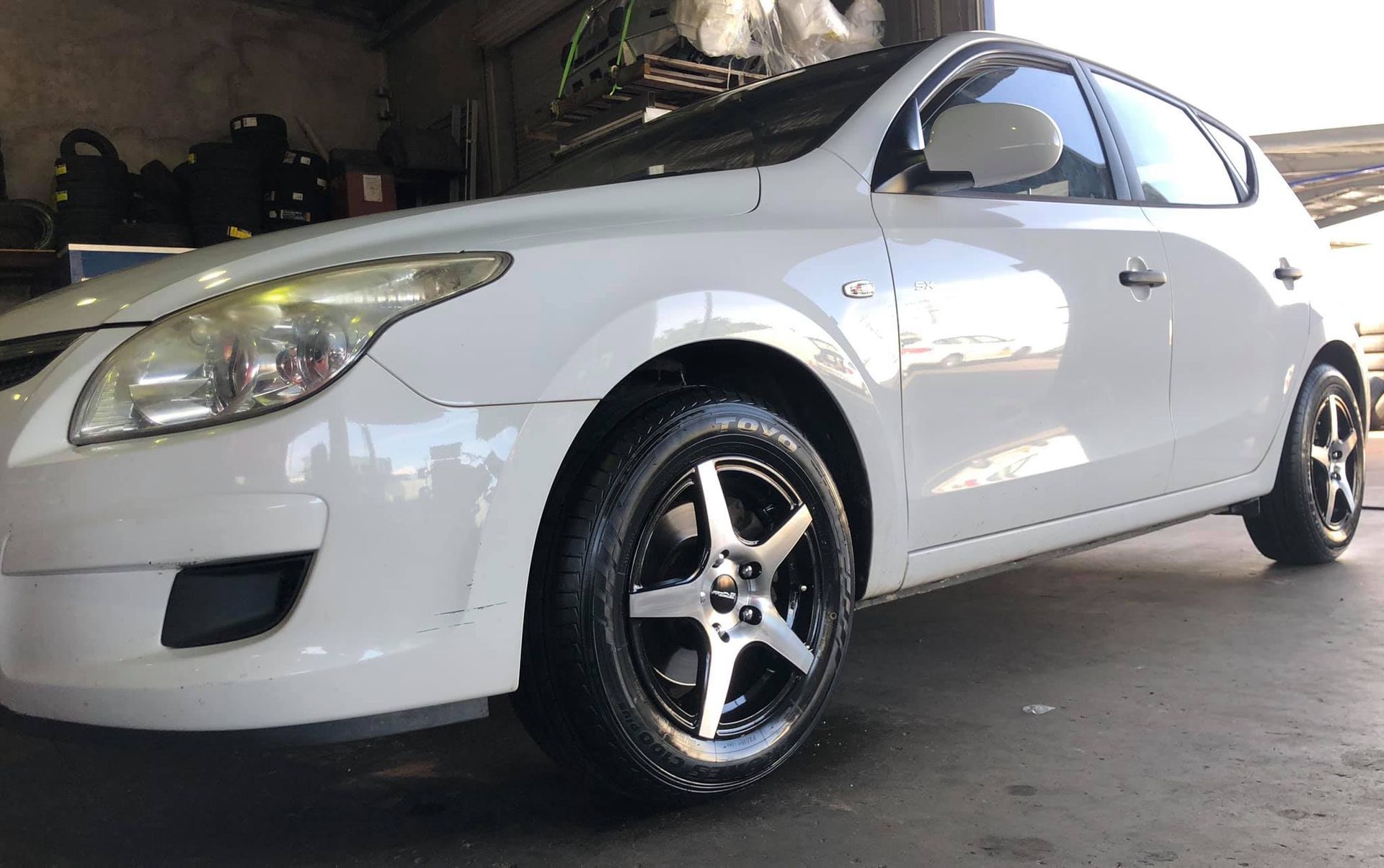 A White Car With Black Wheels Is Parked In A Garage — Torque Tyres & Trailer Spares Mackay in Mackay, QLD