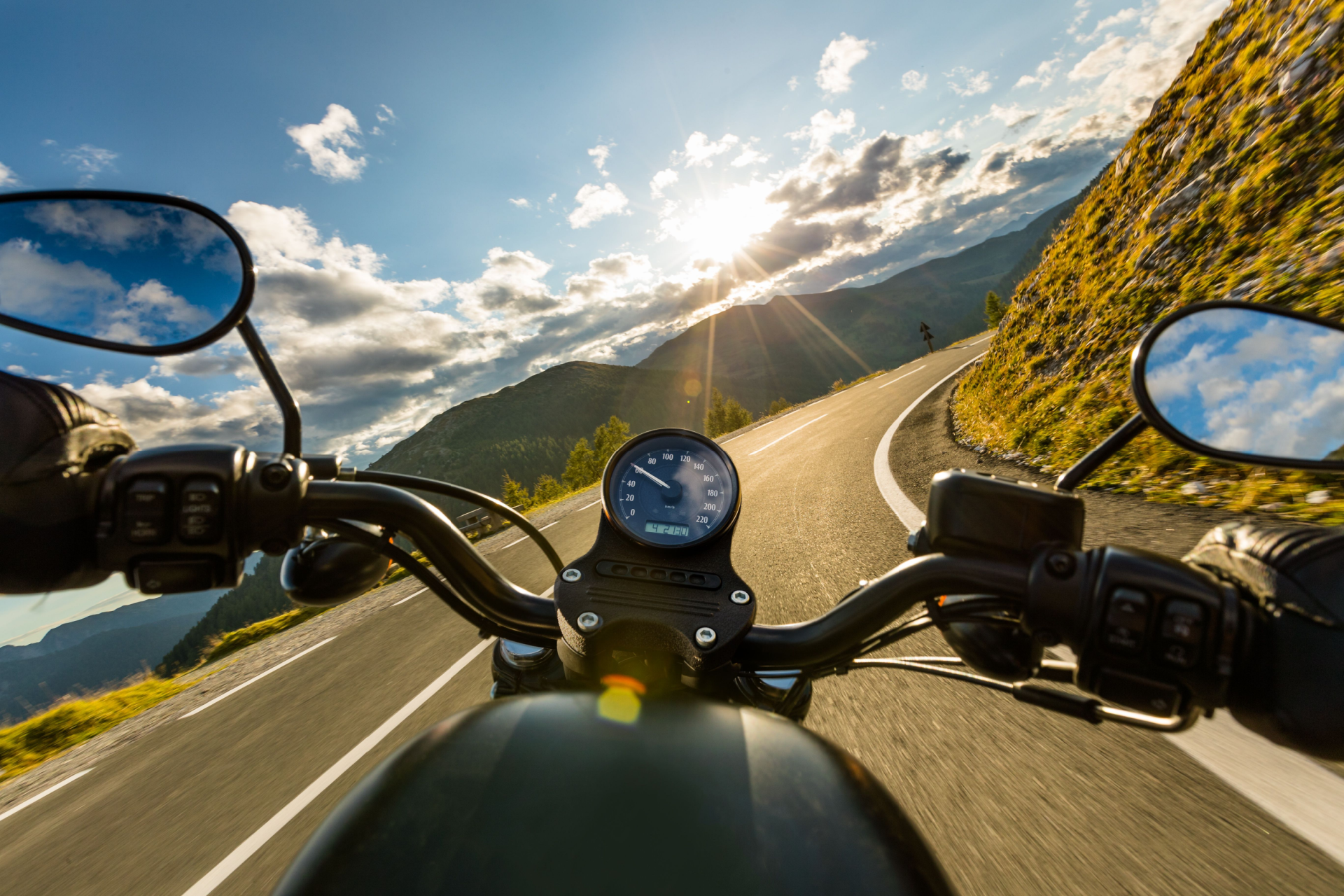 A person is riding a motorcycle down a mountain road.